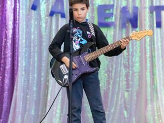 student performing guitar on stage