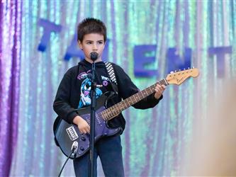 student performing guitar on stage