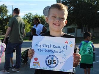 student holding first day of school sign