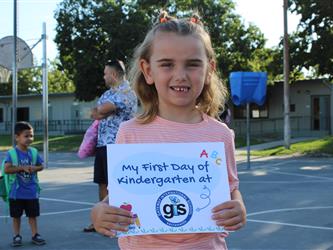 student holding first day of school sign