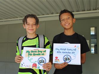 students holding back to school sign 
