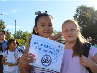 student holding first day of school sign